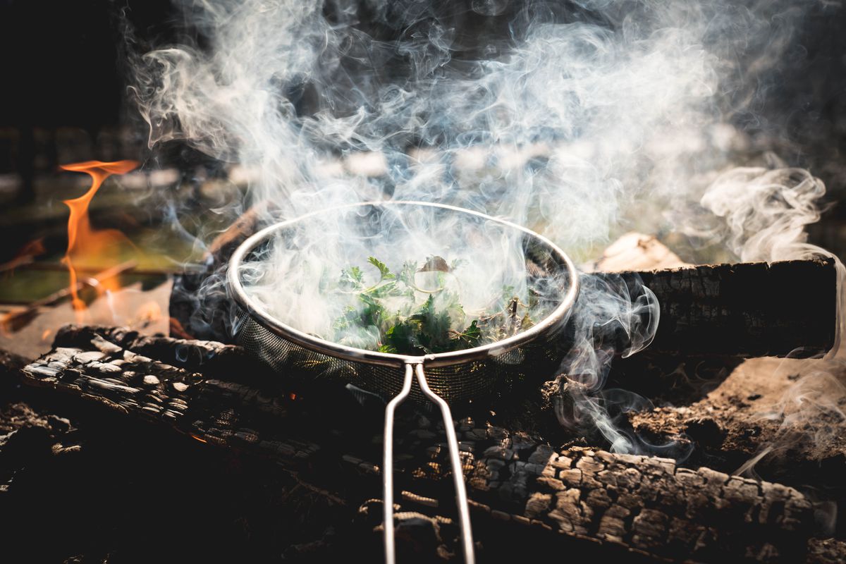 Metal pan on a wood fire creates smokes in the air.