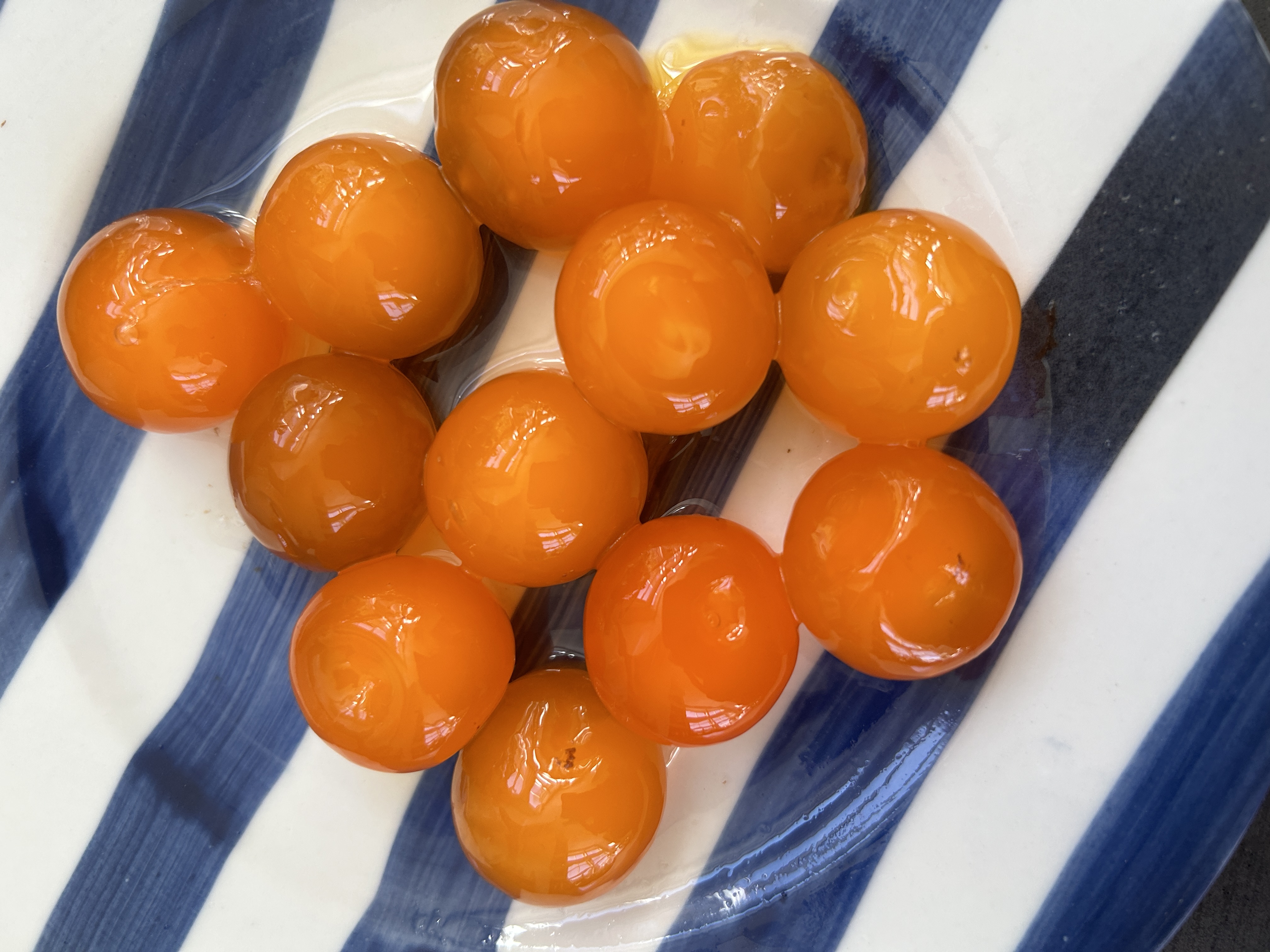 A group of salted egg yolks on a blue and white striped plate.