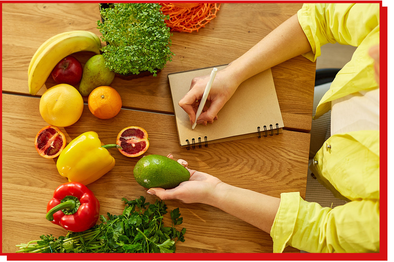 An overhead shot of a person with a note pad and a selection of produce